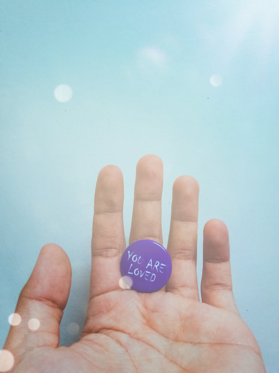 person holding purple badge you are loved text printed